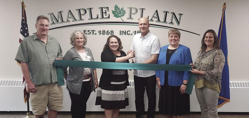 Group of WHCC members cutting a ribbon in the Maple Plain council chamber.