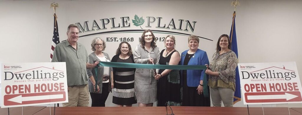 Group of WHCC members cutting a ribbon in the Maple Plain council chamber.
